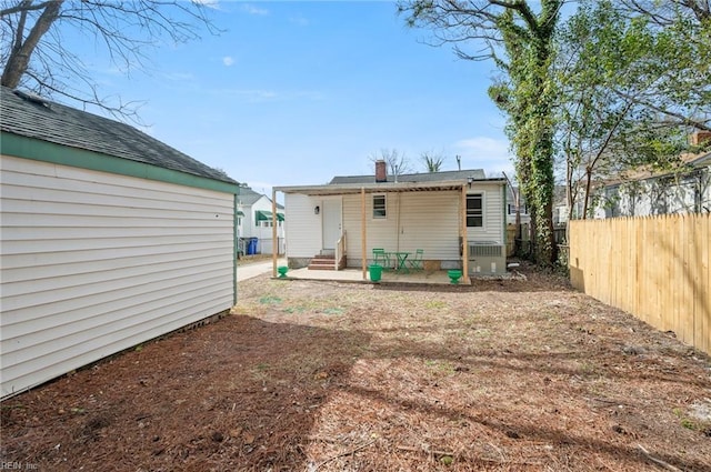 rear view of house with entry steps, cooling unit, and fence