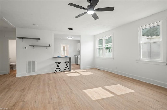 unfurnished living room featuring baseboards, visible vents, and light wood finished floors