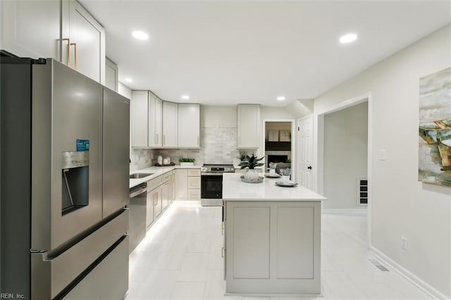 kitchen featuring stainless steel appliances, backsplash, a center island, and light countertops