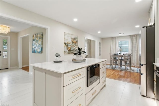 kitchen with a kitchen island, recessed lighting, freestanding refrigerator, light countertops, and white cabinetry