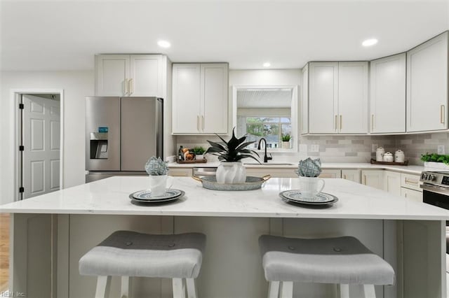 kitchen with decorative backsplash, a breakfast bar, appliances with stainless steel finishes, and a sink