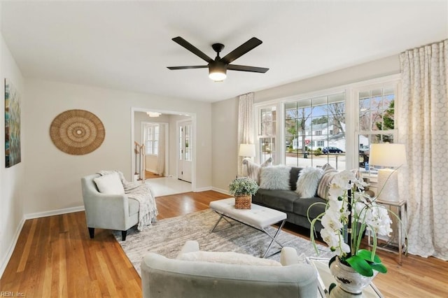 living area with wood finished floors, baseboards, and ceiling fan