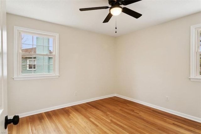 spare room featuring a ceiling fan, light wood-type flooring, and baseboards