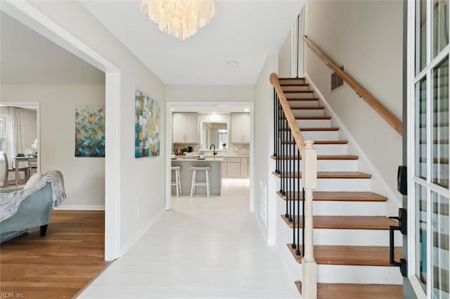 foyer featuring light wood-type flooring, baseboards, visible vents, and stairs