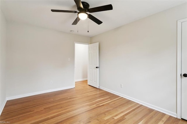 spare room with ceiling fan, light wood-type flooring, and baseboards