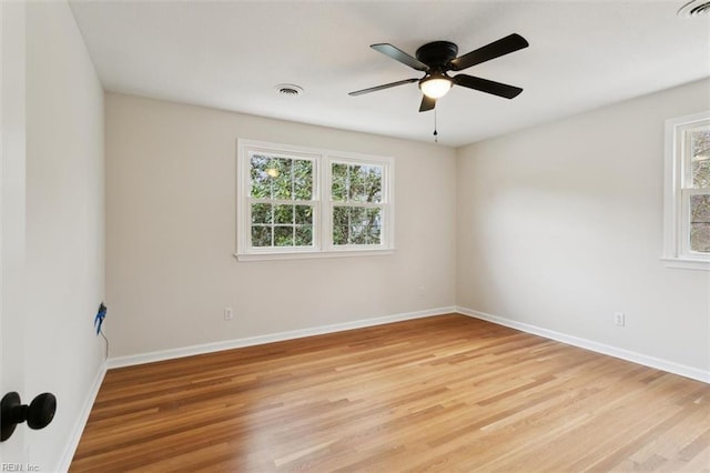 empty room with a wealth of natural light, visible vents, and light wood finished floors