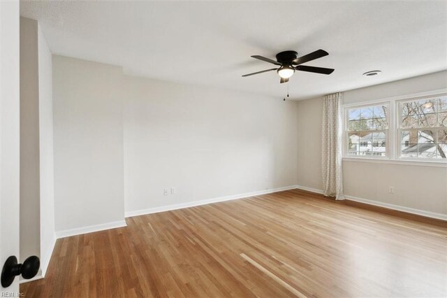 spare room with visible vents, light wood-style flooring, baseboards, and ceiling fan