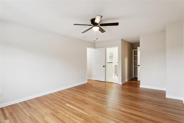 empty room with light wood finished floors, a ceiling fan, and baseboards