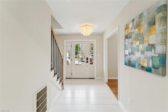 entrance foyer featuring light tile patterned floors, baseboards, a chandelier, and stairs