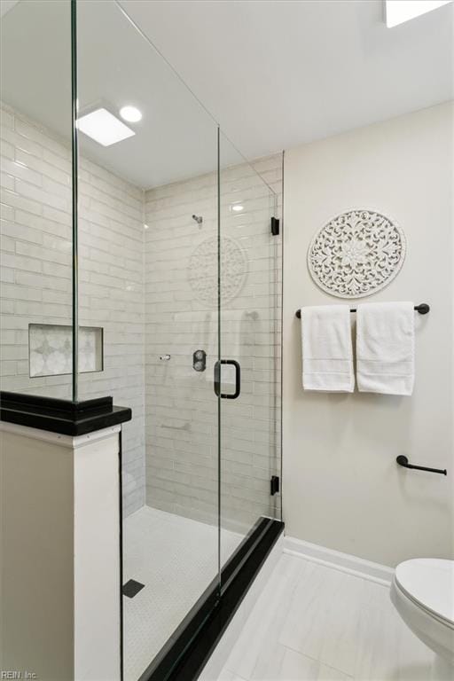 bathroom with toilet, baseboards, and a stall shower