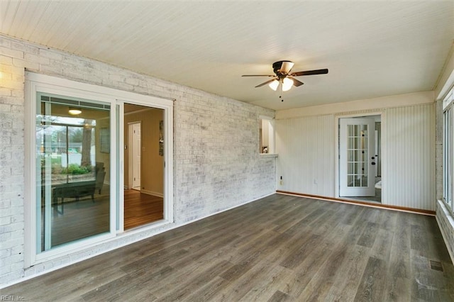 spare room with wood finished floors, brick wall, and ceiling fan