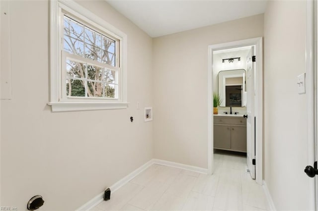 laundry area featuring washer hookup, laundry area, baseboards, and a sink