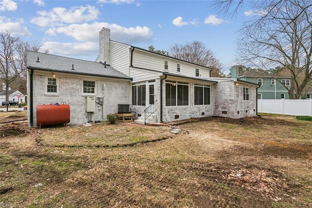 back of house featuring fence, cooling unit, a chimney, a sunroom, and heating fuel