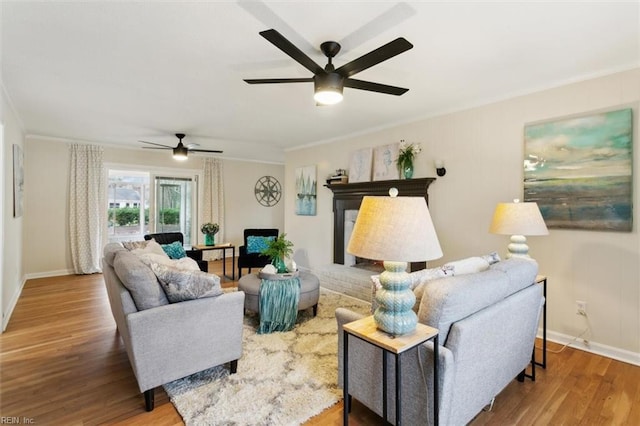 living room featuring ornamental molding, baseboards, a ceiling fan, and wood finished floors