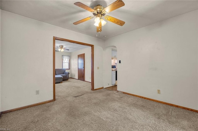 unfurnished room with baseboards, light colored carpet, arched walkways, and ceiling fan