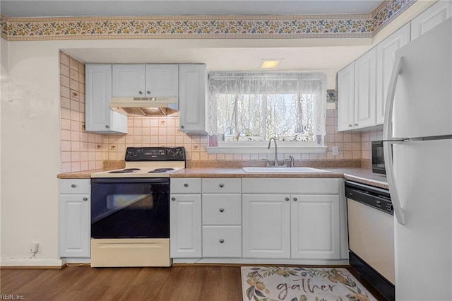 kitchen featuring dark wood-type flooring, under cabinet range hood, a sink, white cabinetry, and white appliances