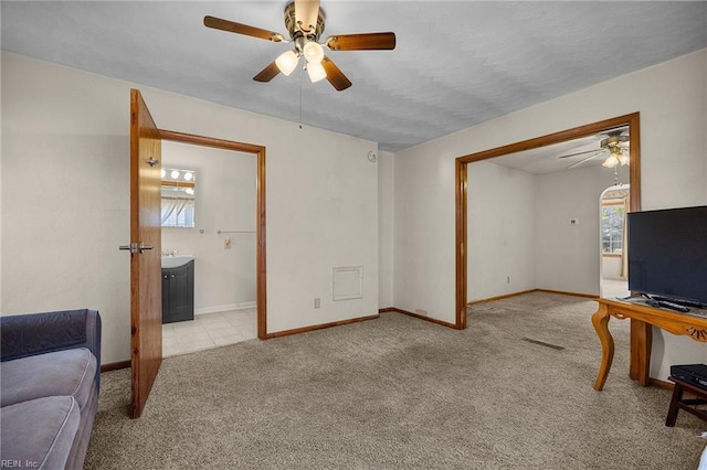 carpeted living room featuring visible vents, baseboards, ceiling fan, and a sink