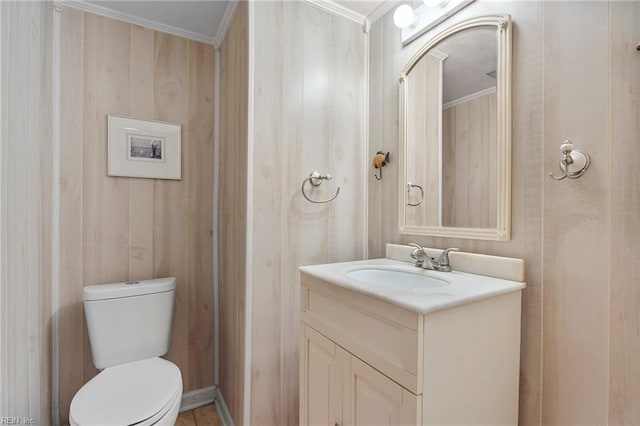 half bathroom featuring crown molding, toilet, and vanity