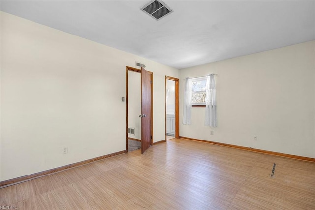 spare room with visible vents, baseboards, and light wood finished floors