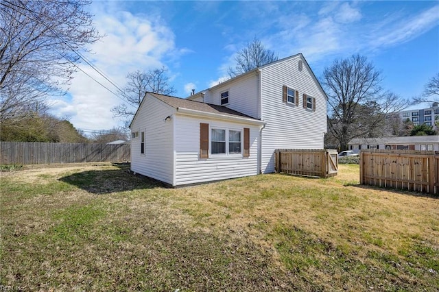 rear view of house featuring a lawn and fence