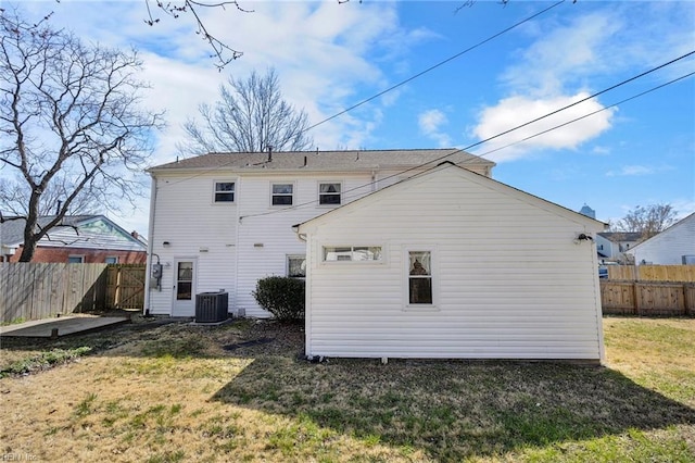 rear view of house featuring central air condition unit, an outdoor structure, a yard, and fence