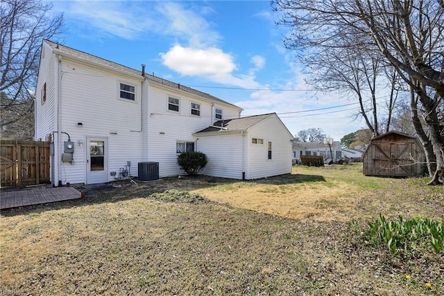 back of property featuring fence, a shed, central air condition unit, a lawn, and an outbuilding