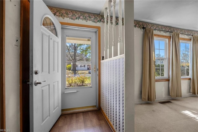 entryway with wood finished floors, baseboards, and visible vents