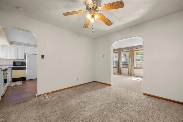 empty room with baseboards, arched walkways, light colored carpet, and ceiling fan