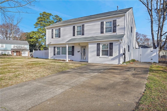 colonial home featuring fence, brick siding, a front lawn, and a gate