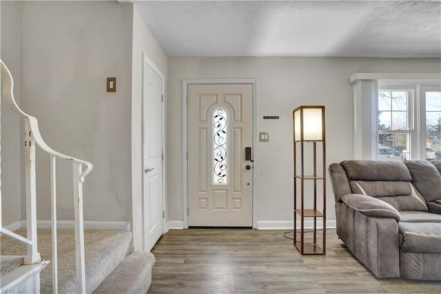 entryway with a textured ceiling, stairs, baseboards, and wood finished floors