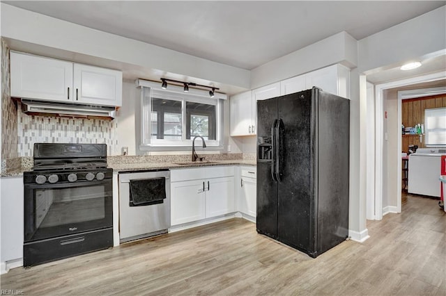 kitchen with black appliances, a sink, light stone counters, under cabinet range hood, and light wood finished floors