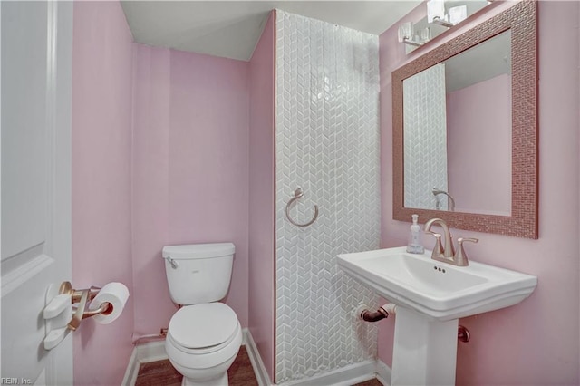 bathroom featuring toilet, baseboards, and a sink