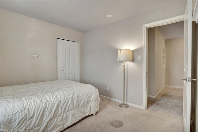 bedroom with baseboards, light carpet, and a closet