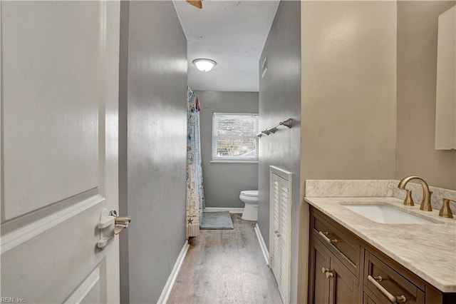 bathroom with vanity, a shower with shower curtain, wood finished floors, baseboards, and toilet