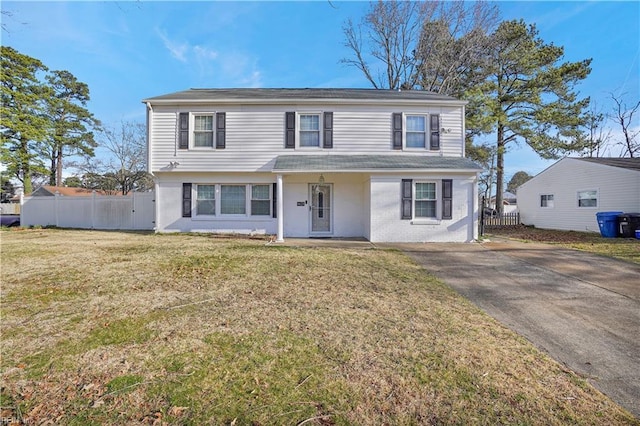 view of front of property with brick siding, driveway, a front lawn, and fence