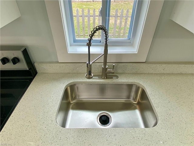 interior details featuring light stone counters and a sink