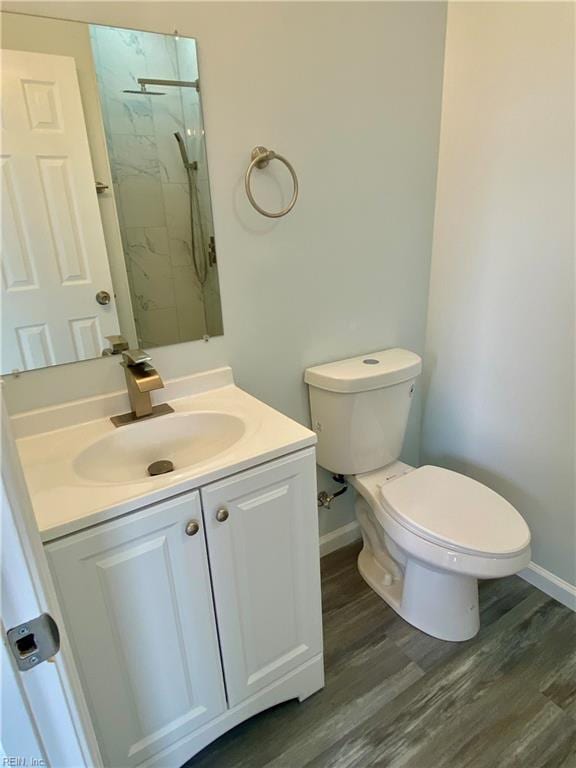 bathroom featuring a marble finish shower, toilet, vanity, and wood finished floors