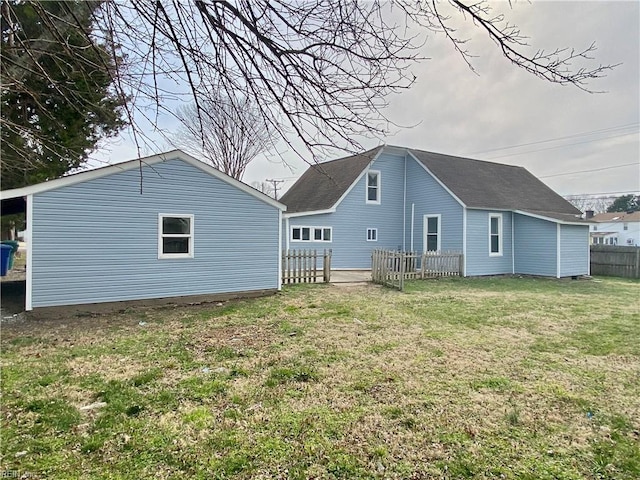 rear view of house with a lawn and fence