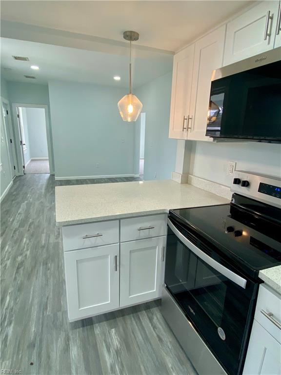 kitchen with white cabinetry, a peninsula, wood finished floors, and stainless steel range with electric cooktop