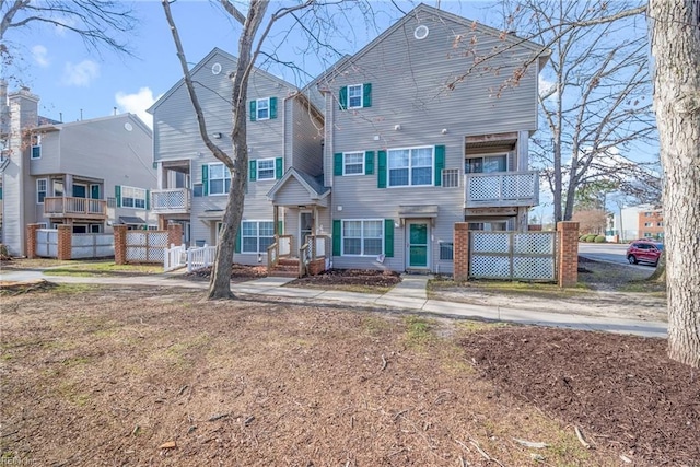 view of front of house featuring a balcony, fence, and a residential view