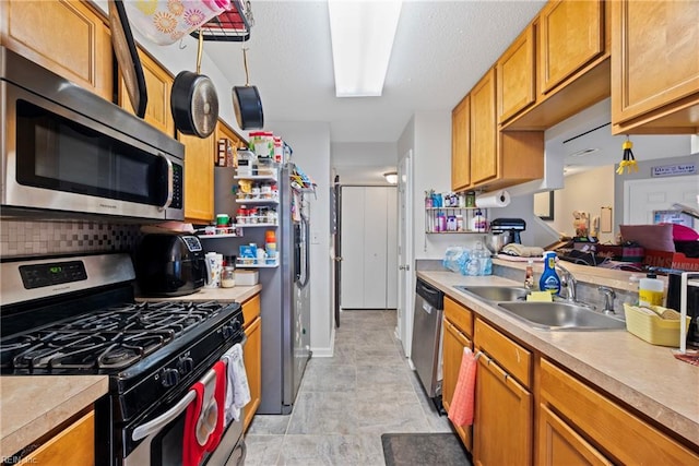 kitchen with tasteful backsplash, appliances with stainless steel finishes, light countertops, and a sink