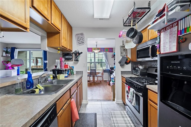 kitchen with visible vents, brown cabinets, stainless steel appliances, a textured ceiling, and a sink