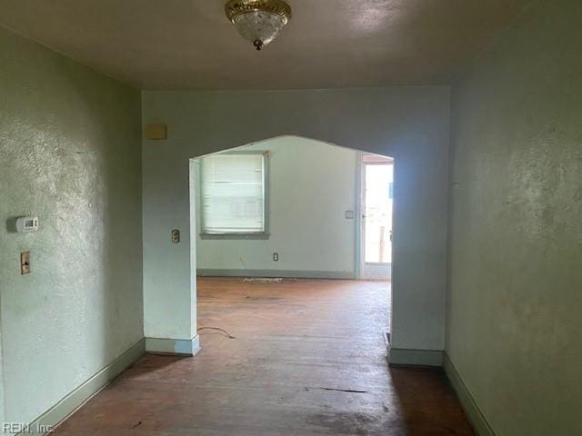 interior space with baseboards, wood finished floors, and a textured wall