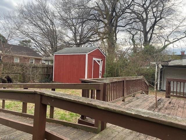 deck featuring a shed, an outdoor structure, and fence