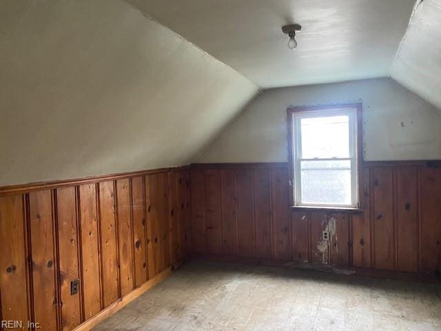 bonus room with wooden walls, wainscoting, and vaulted ceiling