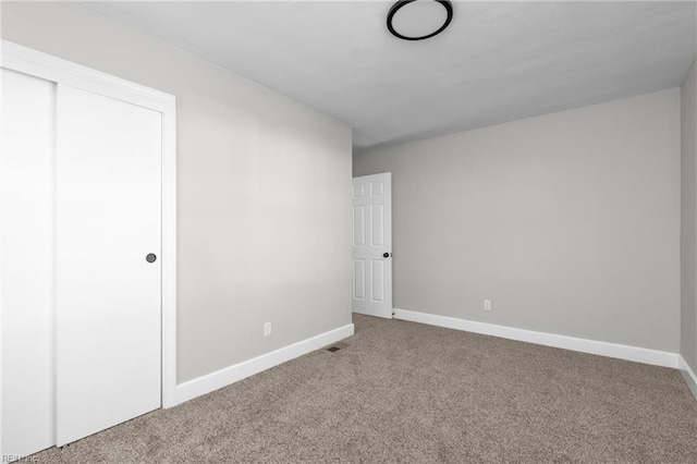 unfurnished bedroom with a closet, baseboards, and carpet