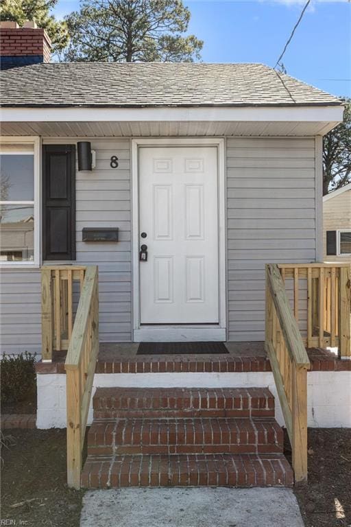 entrance to property featuring a shingled roof