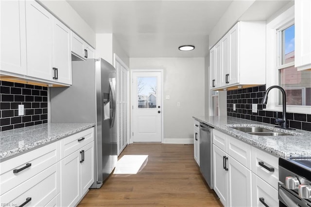 kitchen featuring a sink, stainless steel appliances, light wood finished floors, and white cabinetry