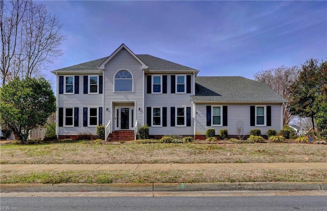 colonial home featuring a shingled roof