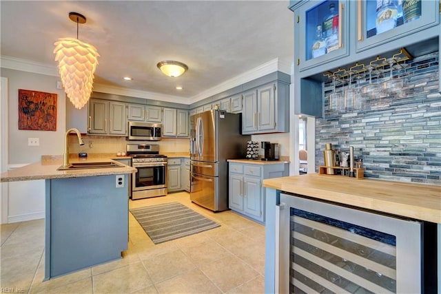 kitchen with ornamental molding, gray cabinetry, a sink, wine cooler, and appliances with stainless steel finishes